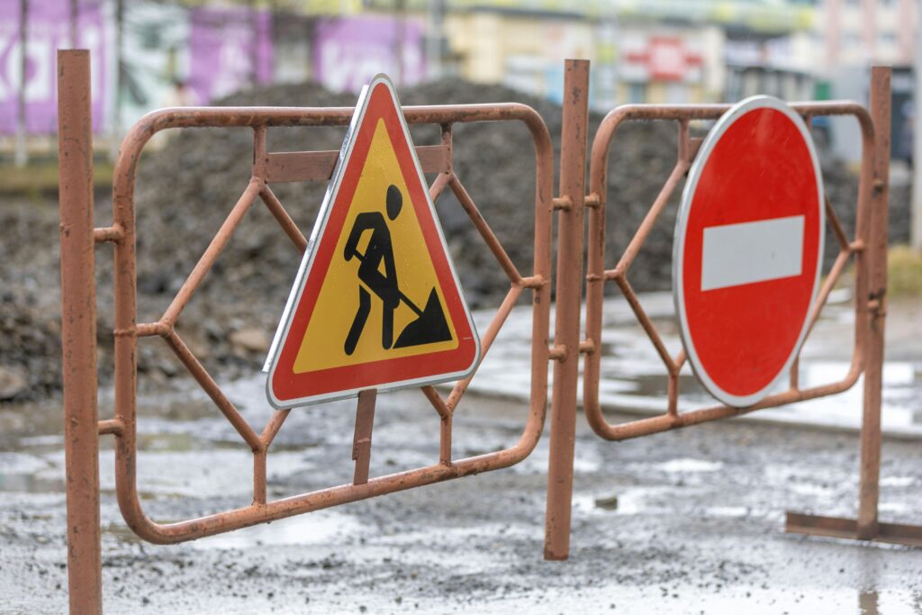 Traffic signs indicating a construction zone and no entry on a rainy day.